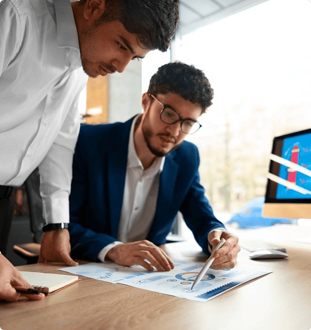 Two finance professionals reviewing printed charts at a desk
