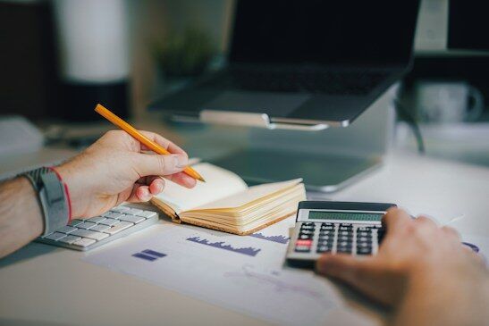 Accountant writing notes beside a calculator