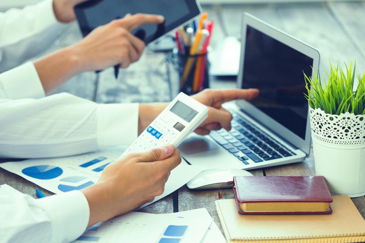 Calculator, laptop and financial charts on a desk