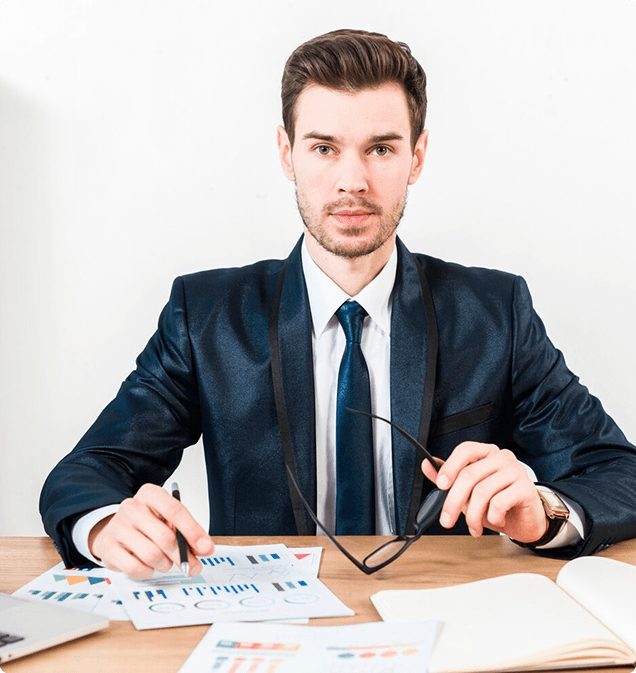 Finance professional in a suit at his desk with financial charts and a laptop