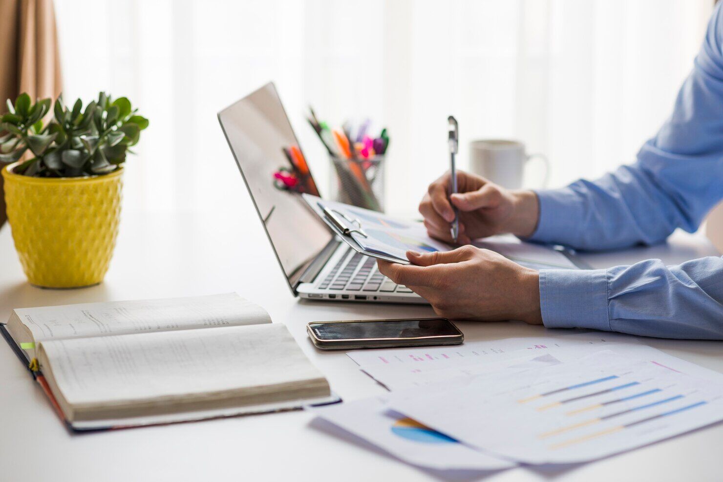 Laptop, notebook and plant on an office desk