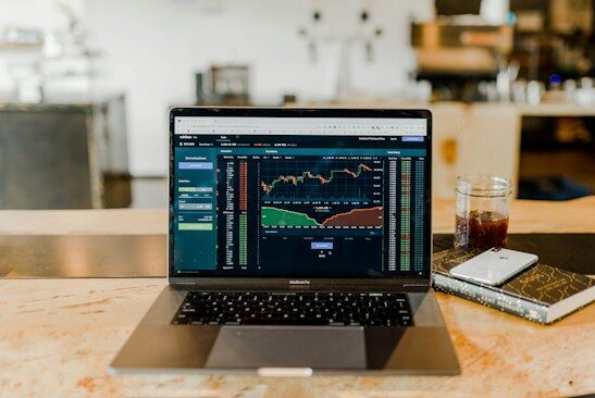 Laptop showing stock market charts on a desk