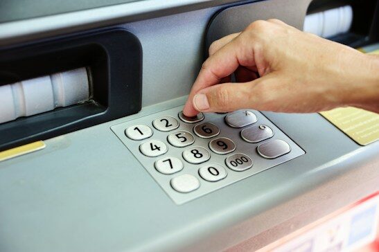 Hand entering a PIN on an ATM keypad