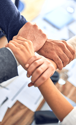 Team members joining hands over a desk
