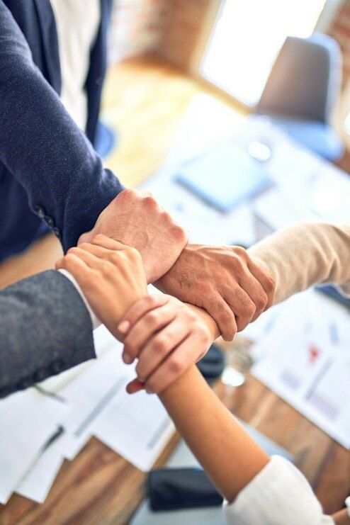 Team members joining hands over a desk